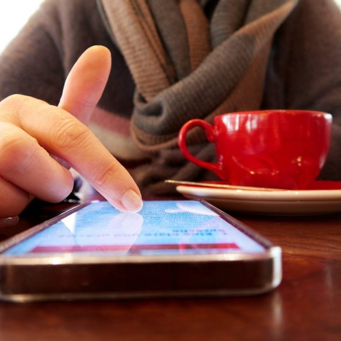 Person using a smartphone with a cup of coffee.